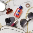 Cuticura Original Floral & Fruity hand gel by handbag next to a phone and sunglasses
