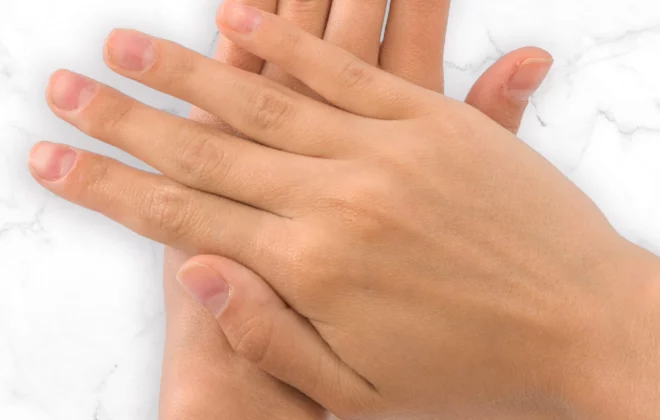 A close up of a pair of hands with smooth looking skin placed on a marble surface.