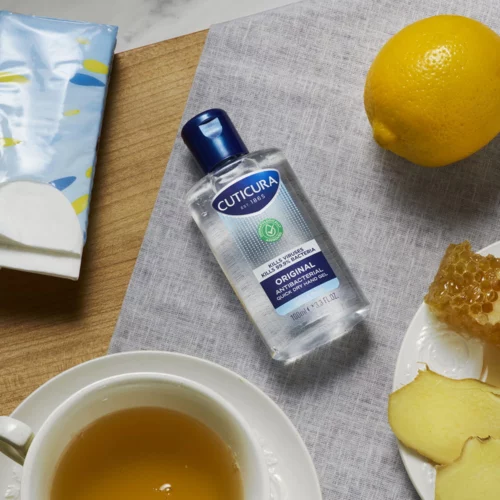 Cuticura Original Antibacterial quick dry hand gel 100ml on a table next to tissues and a lemon